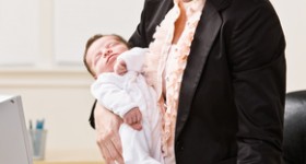Businesswoman holding baby at desk