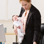 Businesswoman holding baby at desk