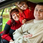 Married couple and  little girl sit in car in park