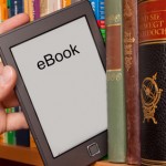 eBook vs Buch, e-Reader aus einem Bücherregal ziehen